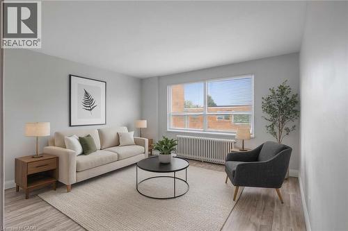 Virtually staged Living room featuring and laminate flooring and large window - 57 Mericourt Road Unit# 310, Hamilton, ON 