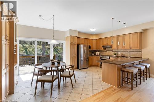 Kitchen featuring wood cabinetry, stainless steel appliances, a stone countertop, and tile flooring - 227 Chestnut Hill Crescent, Kitchener, ON 