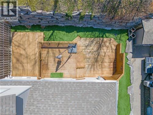 Expansive multi-level wood-finish deck with built-in railing, artificial turf, and a stone retaining wall - 227 Chestnut Hill Crescent, Kitchener, ON 