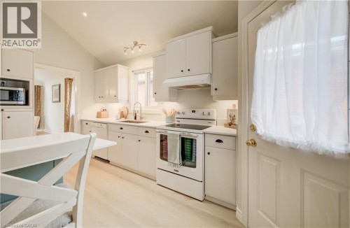 Kitchen featuring white cabinetry, light-toned wood-finish flooring, white appliances, and a vaulted ceiling - 245 Fern Crescent, Waterloo, ON 