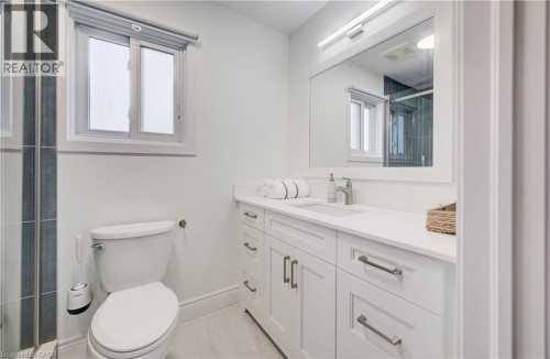 White vanity with shaker-style cabinetry, a single basin sink, and a rectangular mirror with integrated lighting - 245 Fern Crescent, Waterloo, ON 