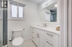 White vanity with shaker-style cabinetry, a single basin sink, and a rectangular mirror with integrated lighting - 