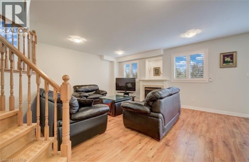 Wood-finish flooring, staircase with natural wood balusters, recessed lighting, and a fireplace with a mantel - 245 Fern Crescent, Waterloo, ON 