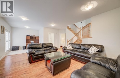 Wood-finish flooring throughout, integrated ceiling lighting, built-in shelving, and a wood staircase with balusters - 245 Fern Crescent, Waterloo, ON 