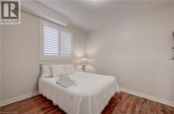Wood-finish flooring with white baseboards, white window shutters, and neutral wall paint - 