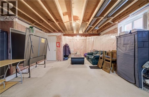 Unfinished basement with exposed ceiling joists, concrete floor, and an egress window - 245 Fern Crescent, Waterloo, ON 