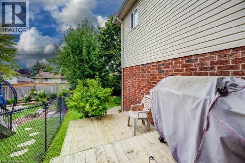 Wood deck, brick and siding exterior, chain link fence, mature landscaping, and a manicured lawn - 245 Fern Crescent, Waterloo, ON 
