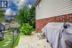 Wood deck, brick and siding exterior, chain link fence, mature landscaping, and a manicured lawn - 