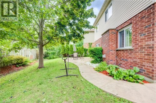 Brick and siding exterior with a concrete pathway, mature trees, and landscaping - 245 Fern Crescent, Waterloo, ON 