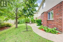 Brick and siding exterior with a concrete pathway, mature trees, and landscaping - 