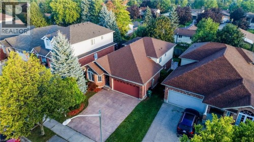 Brick exterior residence with a two-car garage, mature landscaping, and a paved driveway - 245 Fern Crescent, Waterloo, ON 