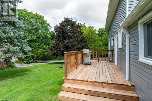 Wood deck with railing and steps to the lawn, gray horizontal siding, white trim around windows, and a white downspout - 146 Benson Street, Ingersoll, ON 