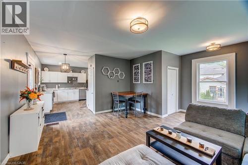 Wood-finish flooring throughout, white kitchen cabinetry, stainless steel dishwasher, and a ceiling-mounted light fixture - 146 Benson Street, Ingersoll, ON 