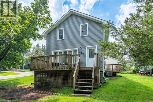 Gable-roof home featuring horizontal siding, a multi-level wood deck with lattice skirting, and mature trees on a grassy lot - 146 Benson Street, Ingersoll, ON 