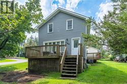 Gable-roof home featuring horizontal siding, a multi-level wood deck with lattice skirting, and mature trees on a grassy lot - 
