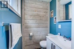 Powder room featuring a wood-panel accent wall, a white vanity with a rectangular sink, and a chrome faucet - 