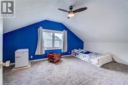 Sloped ceiling room featuring a ceiling fan with integrated lighting, a window with curtains, and textured carpeting - 