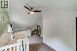 Sloped ceilings with a ceiling fan light fixture, carpeted flooring, and a window with white trim - 