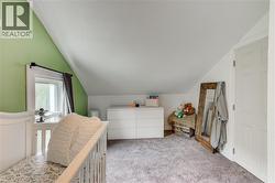 Bedroom with sloped ceilings, a window with trim, soft gray carpeting, and a paneled door - 