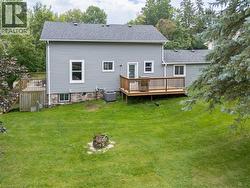 Expansive lawn with a built-in fire pit, multiple wood decks, and a gray siding exterior - 
