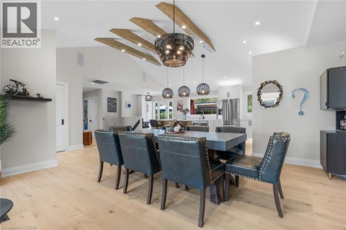 Vaulted ceiling with exposed wood beams, wood-finish flooring, recessed lighting, and a kitchen with white cabinetry and stainless steel appliances - 293 North Shore Boulevard E, Burlington, ON 