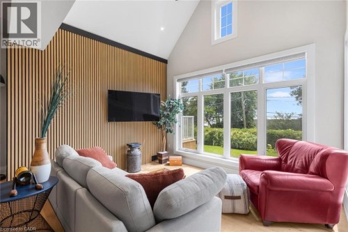 Vaulted ceiling with recessed lighting, full-height slatted wood-finish accent wall, large picture windows, and light wood-finish flooring - 293 North Shore Boulevard E, Burlington, ON 
