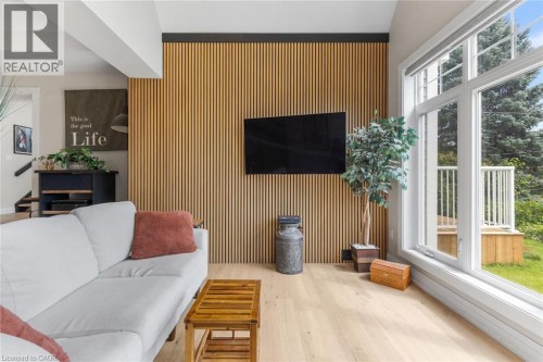 Wood-finish flooring, accent wall with vertical wood paneling, large windows, and a built-in media cabinet - 293 North Shore Boulevard E, Burlington, ON 