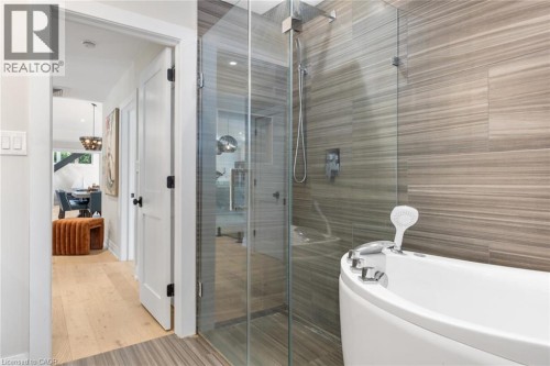 Glass-enclosed shower with a rainfall showerhead, alongside a freestanding soaking tub - 293 North Shore Boulevard E, Burlington, ON 