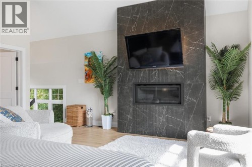 Integrated fireplace within a dark stone-finish accent wall, light wood-finish flooring, and a white interior door with dark hardware - 293 North Shore Boulevard E, Burlington, ON 