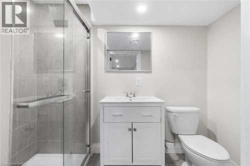 Glass-enclosed shower with gray tiled walls, white vanity with integrated sink, chrome faucet, and recessed lighting - 293 North Shore Boulevard E, Burlington, ON 