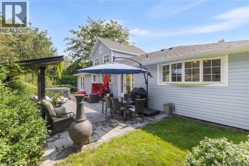 Expansive paver patio with a pergola, built-in hot tub, and lush surrounding landscaping - 293 North Shore Boulevard E, Burlington, ON 