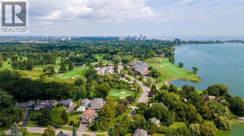 Expansive waterfront property featuring a golf course, mature trees, and a residential area with varied architectural styles - 293 North Shore Boulevard E, Burlington, ON 
