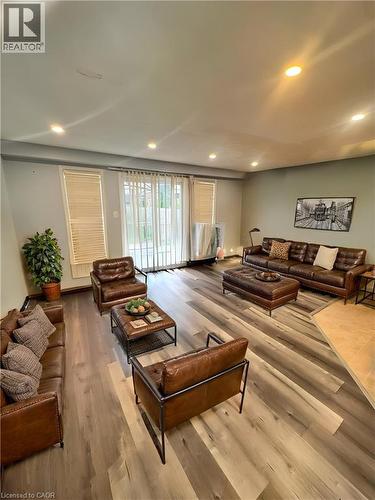 Recessed ceiling lighting, sliding glass door, two window openings with horizontal blinds, wood-finish flooring, and a diagonal transition to tile flooring - 717 Activa Avenue, Kitchener, ON 