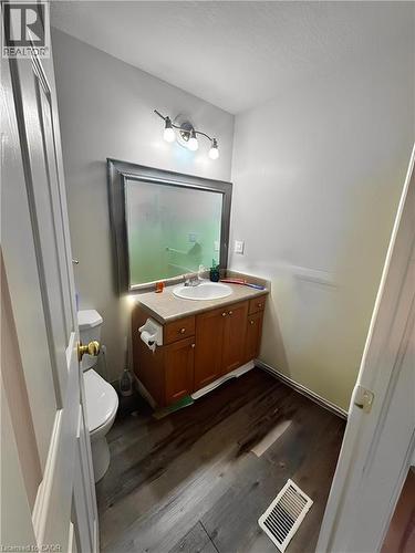 Vanity with integrated sink, wood-finish flooring, wall-mounted light fixture, and framed mirror - 717 Activa Avenue, Kitchener, ON 