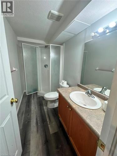 Modern bathroom featuring a wood-finish vanity with an integrated circular sink, stone-textured countertop, and chrome fixtures - 717 Activa Avenue, Kitchener, ON 