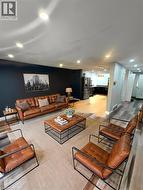 Contemporary living space showcasing a cognac leather sectional sofa, wood-finish coffee table with metal frame, and coordinating leather accent chairs - 