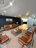 Contemporary living space showcasing a cognac leather sectional sofa, wood-finish coffee table with metal frame, and coordinating leather accent chairs - 717 Activa Avenue, Kitchener, ON 