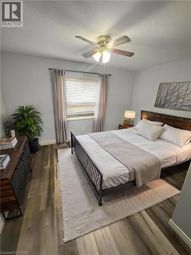 Window with blinds and drapes, wood-finish flooring, ceiling fan with light fixture, and a built-in wood-finish headboard - 717 Activa Avenue, Kitchener, ON 