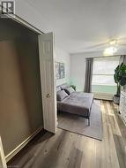 Wood-finish flooring, ceiling fan with integrated lighting, window with blinds and drapes, and a baseboard heater - 