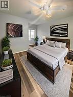 Master bedroom featuring a wood-finish bed frame, neutral bedding, wood-finish flooring throughout, and a ceiling fan with integrated lighting - 