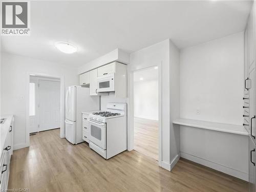 Kitchen featuring wood-finish flooring, white cabinetry, and white appliances - 220 Cairn Street, London, ON 