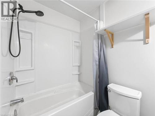 White acrylic tub and shower combination with an integrated soap dish and a black handheld showerhead - 220 Cairn Street, London, ON 
