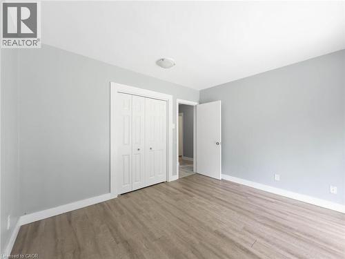 Light gray wall paint, wood-finish flooring, white trim, and a ceiling-mounted light fixture - 220 Cairn Street, London, ON 