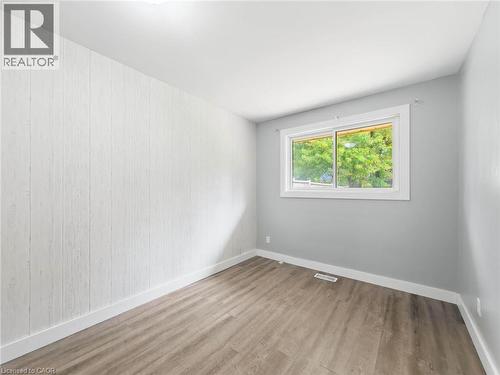 Wood-finish flooring, white paneled accent wall, light gray painted walls, and a sliding window - 220 Cairn Street, London, ON 