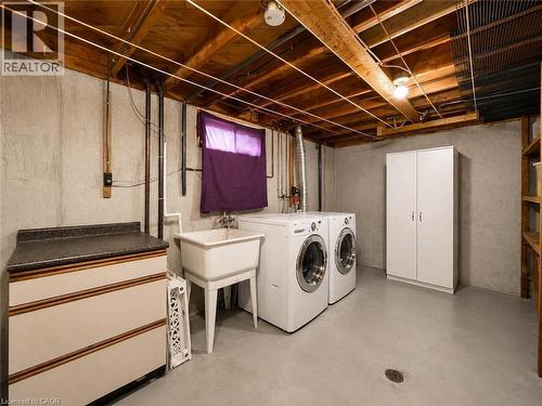 Laundry area featuring concrete flooring, a utility sink, and overhead wood beam ceiling - 220 Cairn Street, London, ON 