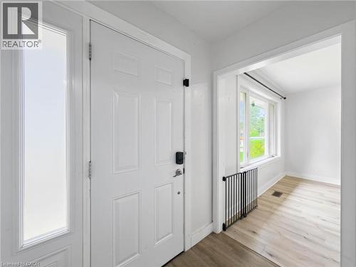 Entry door with frosted glass sidelight, light wood-finish flooring, and bright white walls - 220 Cairn Street, London, ON 