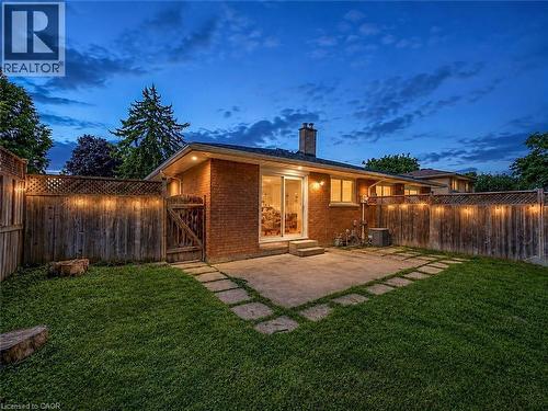 Brick exterior with a concrete patio, sliding glass door, and a grass lawn - 220 Cairn Street, London, ON 