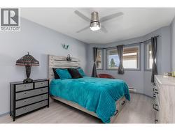The spacious primary bedroom features updated flooring, a ceiling fan and multiple windows. - 