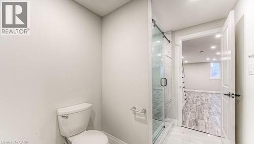 Glass-enclosed shower with a sliding barn door, bright white walls, and white floor tiling - 152 Overlea Drive, Kitchener, ON 
