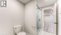 Glass-enclosed shower with a sliding barn door, bright white walls, and white floor tiling - 